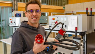 Martin Vieweg hält an einem Arbeitsplatz Kabel in der Hand