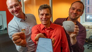 Die drei Gründer der pinpoint GmbH halten ihre Produkte in die Kamera