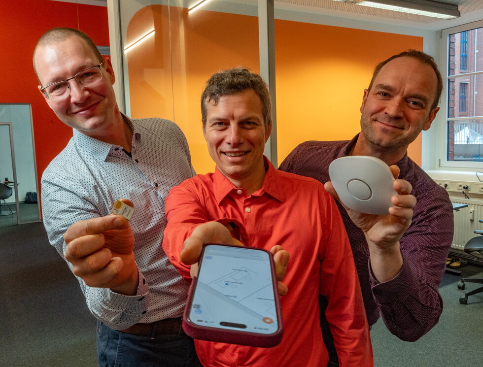 Die drei Gründer der pinpoint GmbH halten ihre Produkte in die Kamera