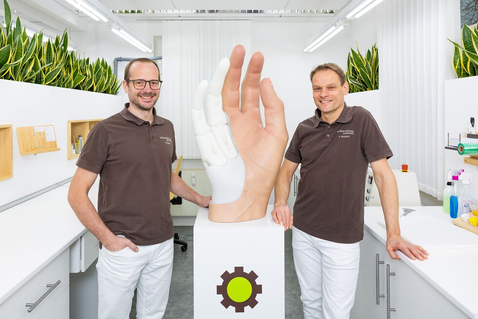 Christoph Braun und Jonas Schubert an einem überlebensgroßen Handmodell